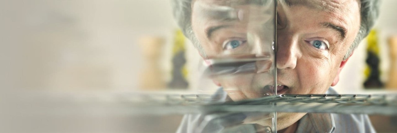 This image depicts the smiling face of a middle aged man peering into a shiny clean oven.